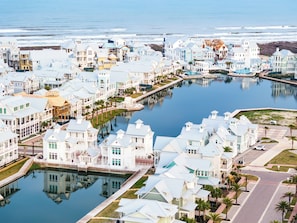 Zona residencial costera con casas a lo largo de un canal, un muelle y una vista despejada del océano.