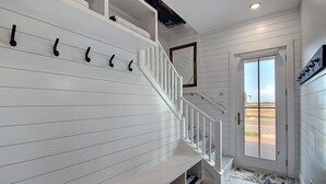 A staircase with white railings and a handrail, leading to a landing with a door and a window. - Bajo El Sol 124 SEV (Port Aransas)