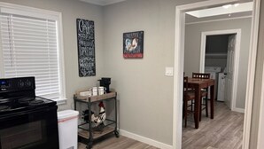 Una cocina con estufa, carrito de café y decoración en la pared.