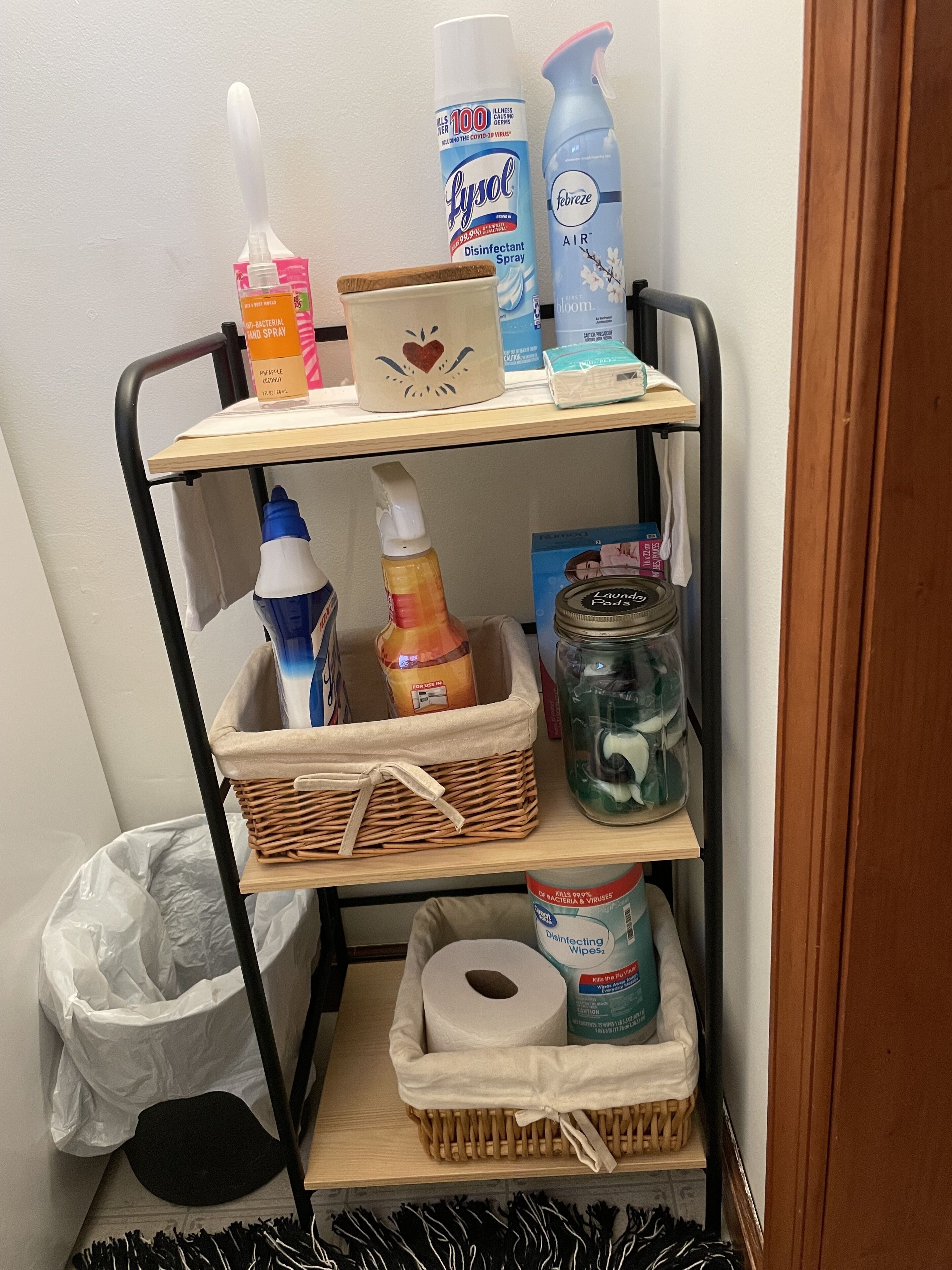 A storage cart with cleaning supplies, including disinfectant sprays, hand sanitizer, and laundry detergent.