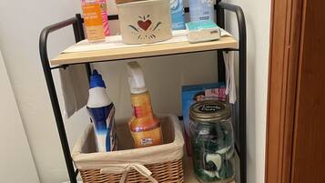 A storage cart with cleaning supplies, including disinfectant sprays, hand sanitizer, and laundry detergent.