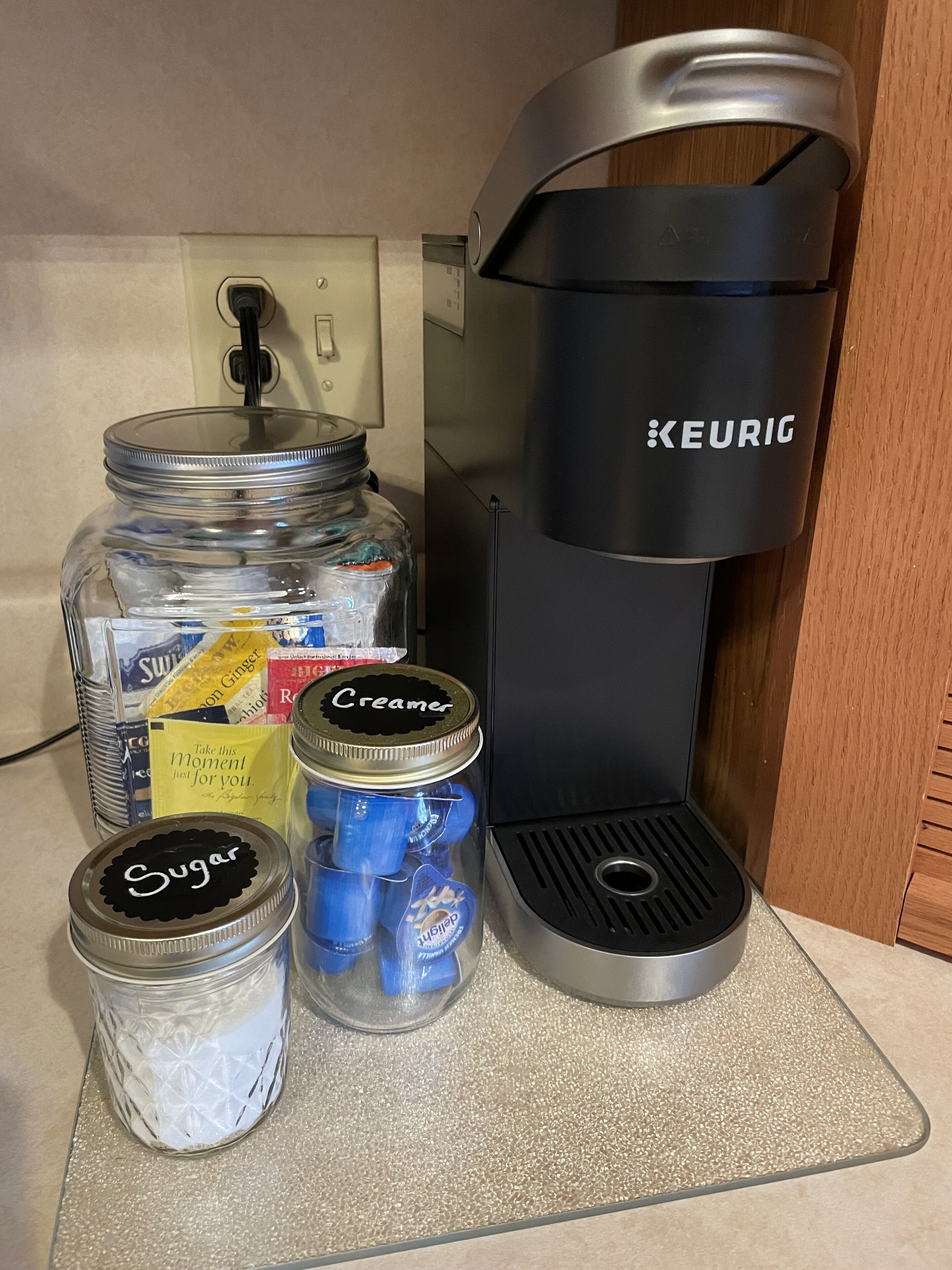 Eine K üchenzeile mit einer Keurig-Kaffeemaschine, einer Zuckerglase, einer Sahnejars und einem Milchaufguss.