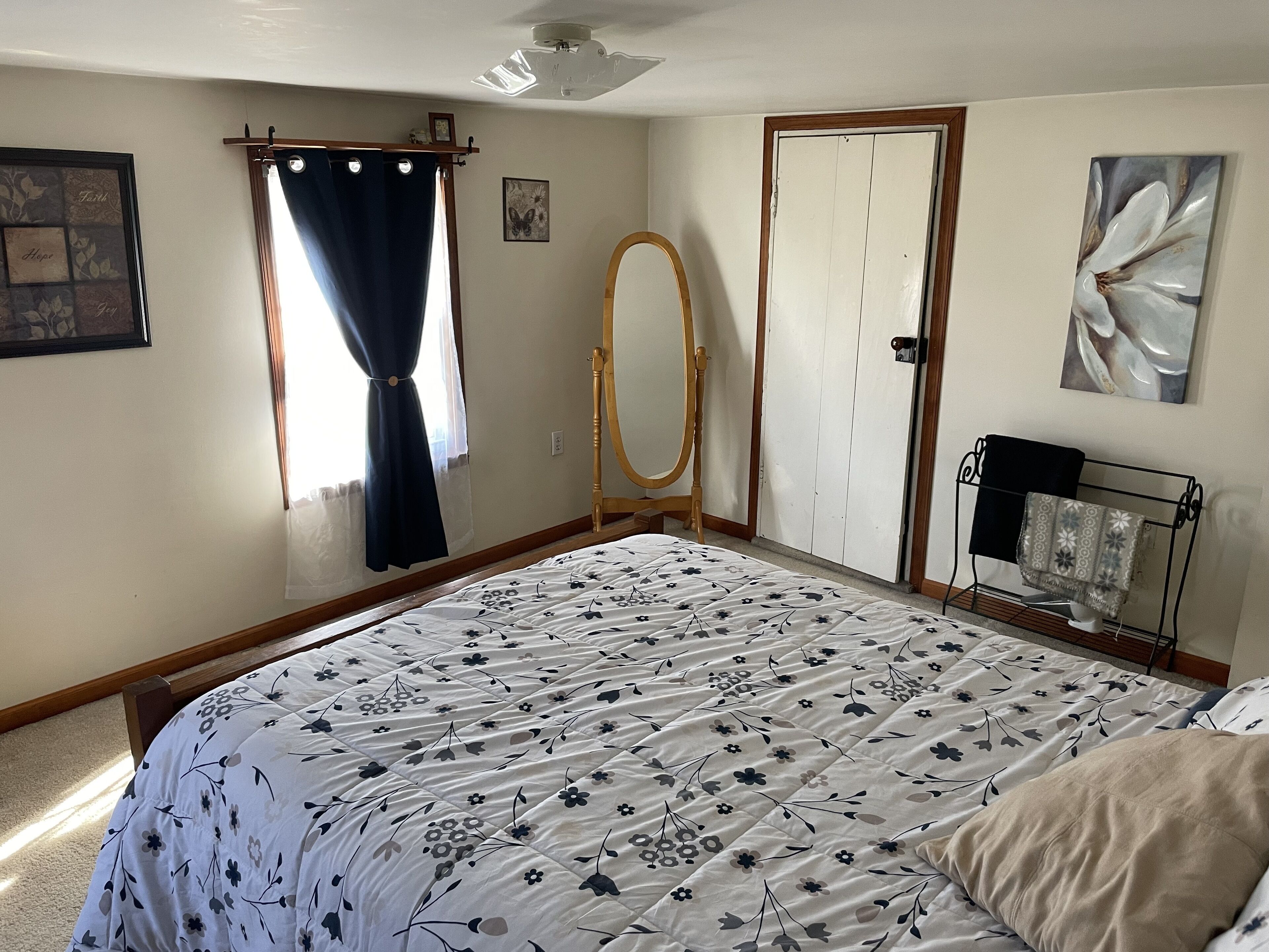 Un dormitorio con cama, armario de madera, espejo, radiador y un cuadro en la pared.