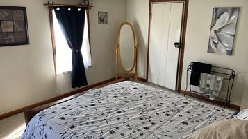 Un dormitorio con cama, armario de madera, espejo, radiador y un cuadro en la pared.