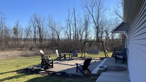 Un espace extérieur aménagé avec des chaises Adirondack, une balançoire et un chien.
