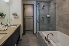 Relax in a spacious bathroom with a bathtub and glass-enclosed shower.
