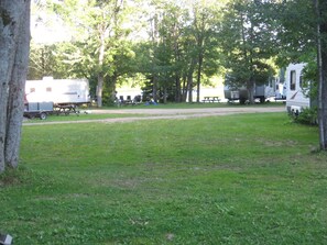 A campground with RVs and trailers, grassy areas, and trees. - The Rockwood Trailer/RV - Sandy Beach + Free Watercraft Use in a Natural Setting (Cloyne)