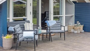 En uteplats med en soffa, två fåtöljer, ett litet bord och korgar av rotting.