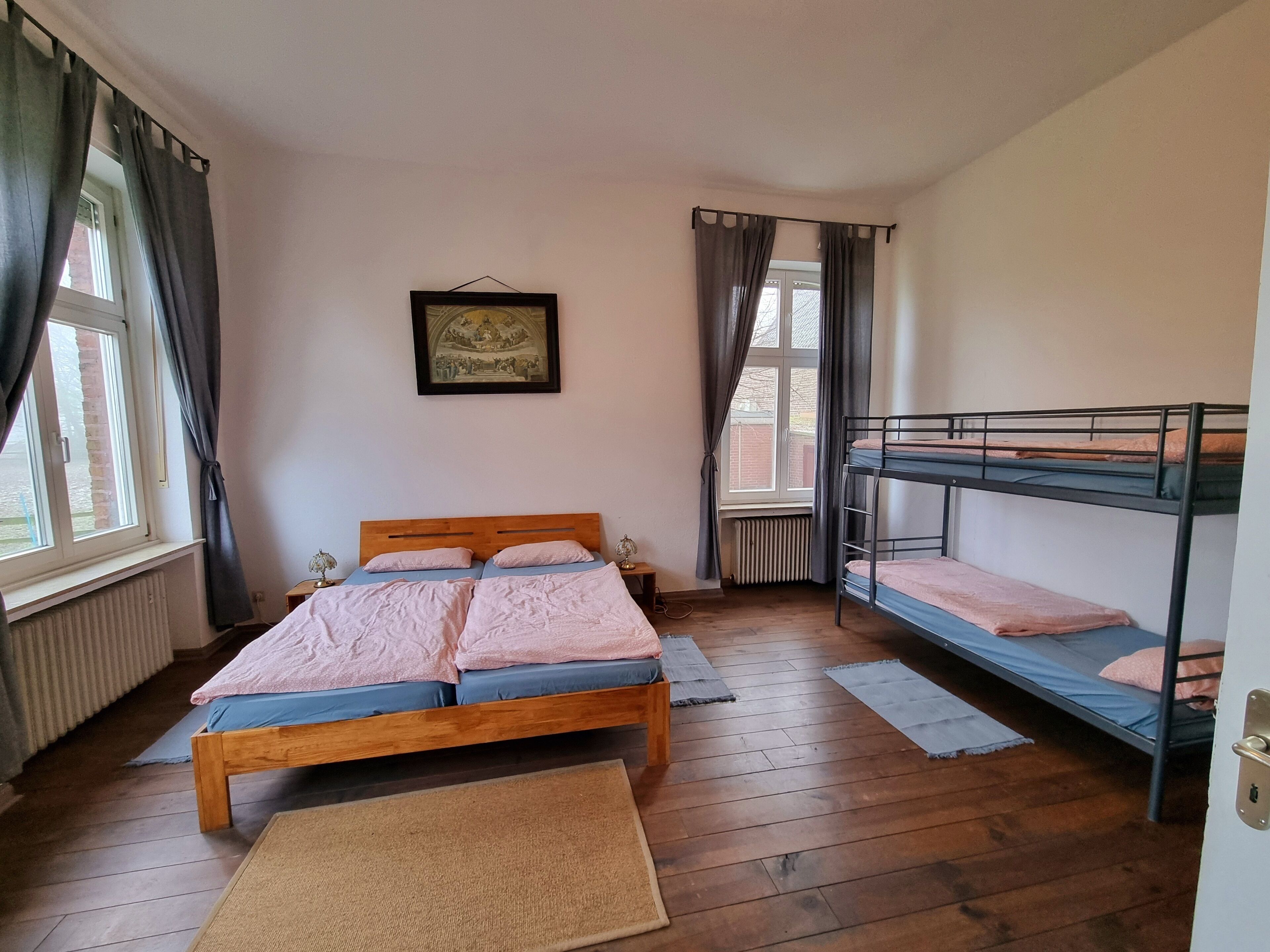 Een kamer met een houten bed, een stapelbed, een radiator en een lijst met een afbeelding aan de muur.