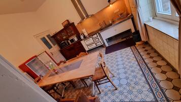 Een keuken met een houten tafel, stoelen, een magnetron en een spoelbak.