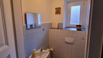 Une petite salle de bain compacte, équipée d’un lavabo, de toilettes et d’une petite fenêtre située au-dessus des toilettes.