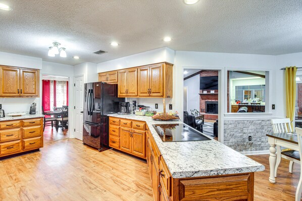A spacious kitchen with wooden cabinets, a granite countertop, and a built-in island. - Home 2.5 Mi to Fort Stewart w/ Heated Pool (Hinesville)