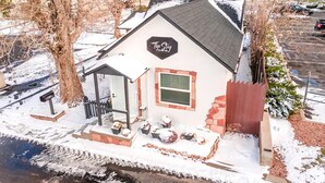 A small, single-story building with a sloped roof, a sign reading "The Stay at Sko", and a covered porch area with outdoor seating. - The Stay at Six•One•Four / Walk right out to Route 66 (Williams)