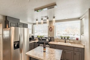 A modern kitchen with stainless steel appliances, a marble countertop, and pendant lighting. - Six•One•Four | Downtown Williams / Walk Route 66 / Pet Friendly (Williams)