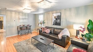 A modern living room with a leather sofa, a coffee table, and a dining area with chairs. - The Stay at Six•One•Four / Walk right out to Route 66 (Williams)