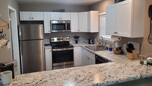 A modern kitchen with white cabinets, stainless steel appliances, and granite countertops. - Pet-Friendly Home for 7 with Fire Pit (Junction)