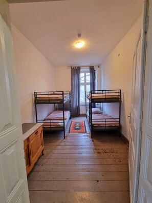 Una habitación pequeña con dos camas literas, un armario de madera y una ventana con cortinas.