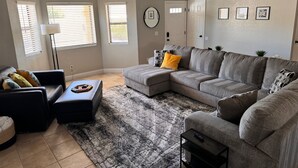 A living room with a sectional sofa, a black leather chair, a coffee table, and a floor lamp. - Lake Havasu Oasis: 3BR, Pool, Hot Tub, Game Room & Boat Parking (Lake Havasu City)