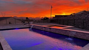 A swimming pool with a waterfall feature, surrounded by a stone wall and a metal fence. - Lake Havasu Oasis: 3BR, Pool, Hot Tub, Game Room & Boat Parking (Lake Havasu City)