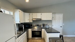 A modern kitchen with white cabinets, stainless steel appliances, and a black countertop. - Lake Havasu Oasis: 3BR, Pool, Hot Tub, Game Room & Boat Parking (Lake Havasu City)