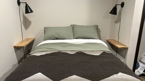 Un lit avec une couverture à motifs géométriques, deux oreillers et deux tables de chevet avec des lampes.