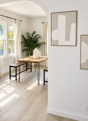 Ein Zimmer mit Esstisch, Stühlen, einer Zimmerpflanze und Bildern an den Wänden.