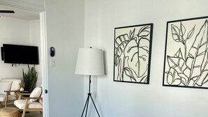 Une chambre à coucher avec un lit, une lampe sur pied et deux œuvres d’art murales.