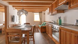 A cozy kitchen with wooden cabinets, a dining table, chairs, and a built-in oven.
