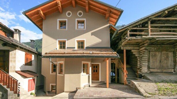 A two-story building with a sloped roof, wooden beams, and a front entrance with steps.