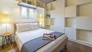 A bedroom with a bed, bedside tables, a tray with breakfast, a window, and built-in storage. - Oasis of Relaxation 1BR Apartment w/pool -Sunrise (Noord)