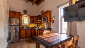 A kitchen with wooden cabinets, a stainless steel refrigerator, a microwave, and a dining table with chairs. - Oasis of Relaxation 1BR Apartment w/pool -Sunrise (Noord)