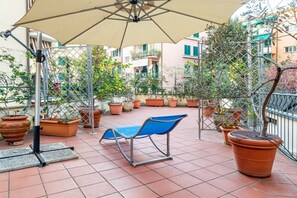 A terrace with a blue chair, a large umbrella, and potted plants. - Nice apartment located on the first floor of a building without elevator (NOT suitable for the disabled) and able to comfortably accommodate up to five people. The accommodation is located in the historic center of Lerici, a few steps from Piazza Mottino (Lerici)