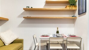 Uma área de refeições compacta com uma mesa branca, quatro cadeiras e uma garrafa de champanhe.