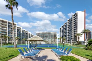 A hotel with multiple floors, outdoor tennis courts, and lounge chairs. - Saida I #105 | Ground-Floor Beachfront Condo • 3 Pools • Direct Beach Access (South Padre Island)