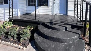 A single-story house with a front porch, a garage door, and a small front yard with plants.