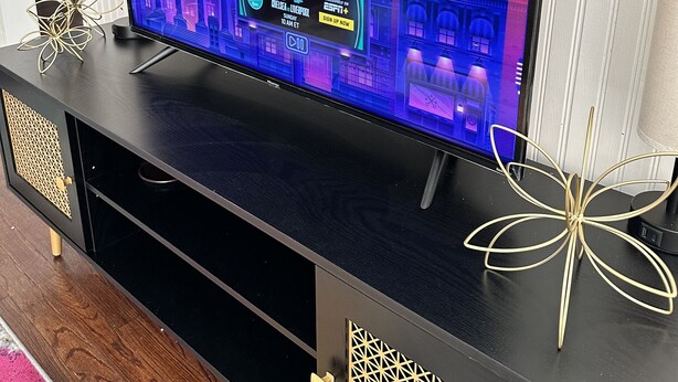 A flat-screen TV on a black entertainment unit with a geometric pattern on the side.