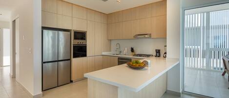 A modern kitchen with stainless steel appliances, wooden cabinets, and a central island with a fruit bowl.