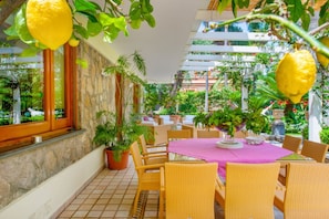 Un patio al aire libre con mobiliario de mimbre, una pared de piedra y plantas en macetas.