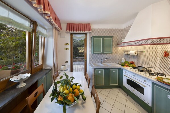 Una cocina con una mesa de comedor lista para cuatro personas, una estufa y un lavabo.