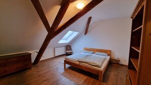 A bedroom with a sloped ceiling, a skylight, a wooden bed, a chair, and a radiator. - Ferienwohnung Jesus - Großzügiges Loft mit Blick auf Burg und Kirchturm (Kevelaer)