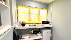 Een kleine keuken met een magnetron, spoelbak en een koelkast.