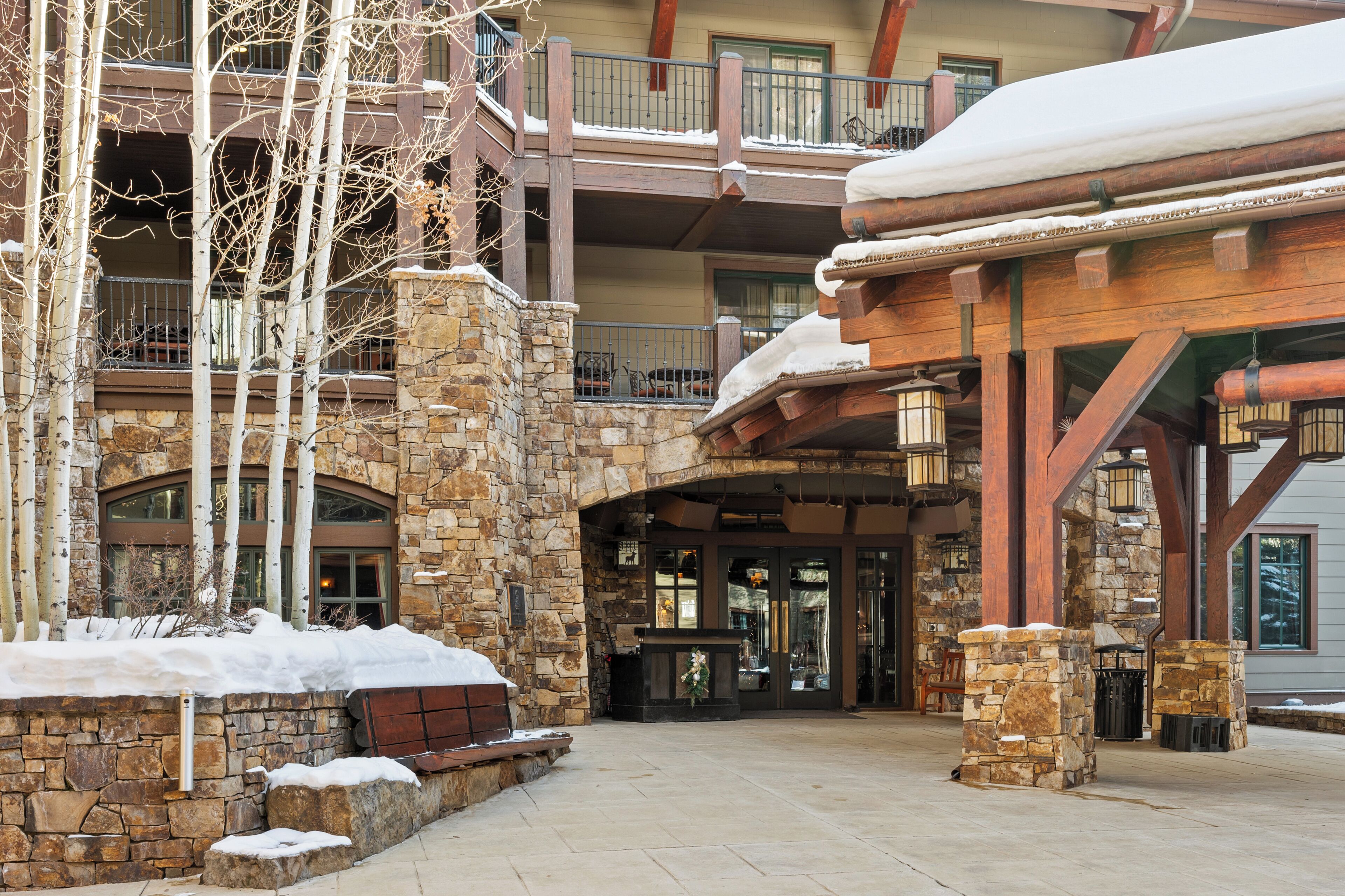 A multi-story building with stone walls, wooden balconies, and a covered entrance area.