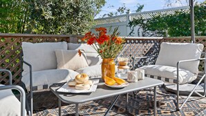 An outdoor seating area with a sofa, chairs, a table, and a decorative vase with flowers. - Charming Urban Bungalow with Garden and Deck (Santa Barbara)