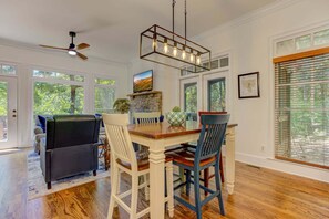 A dining area with a wooden table, chairs, a ceiling fan, and a stone fireplace.