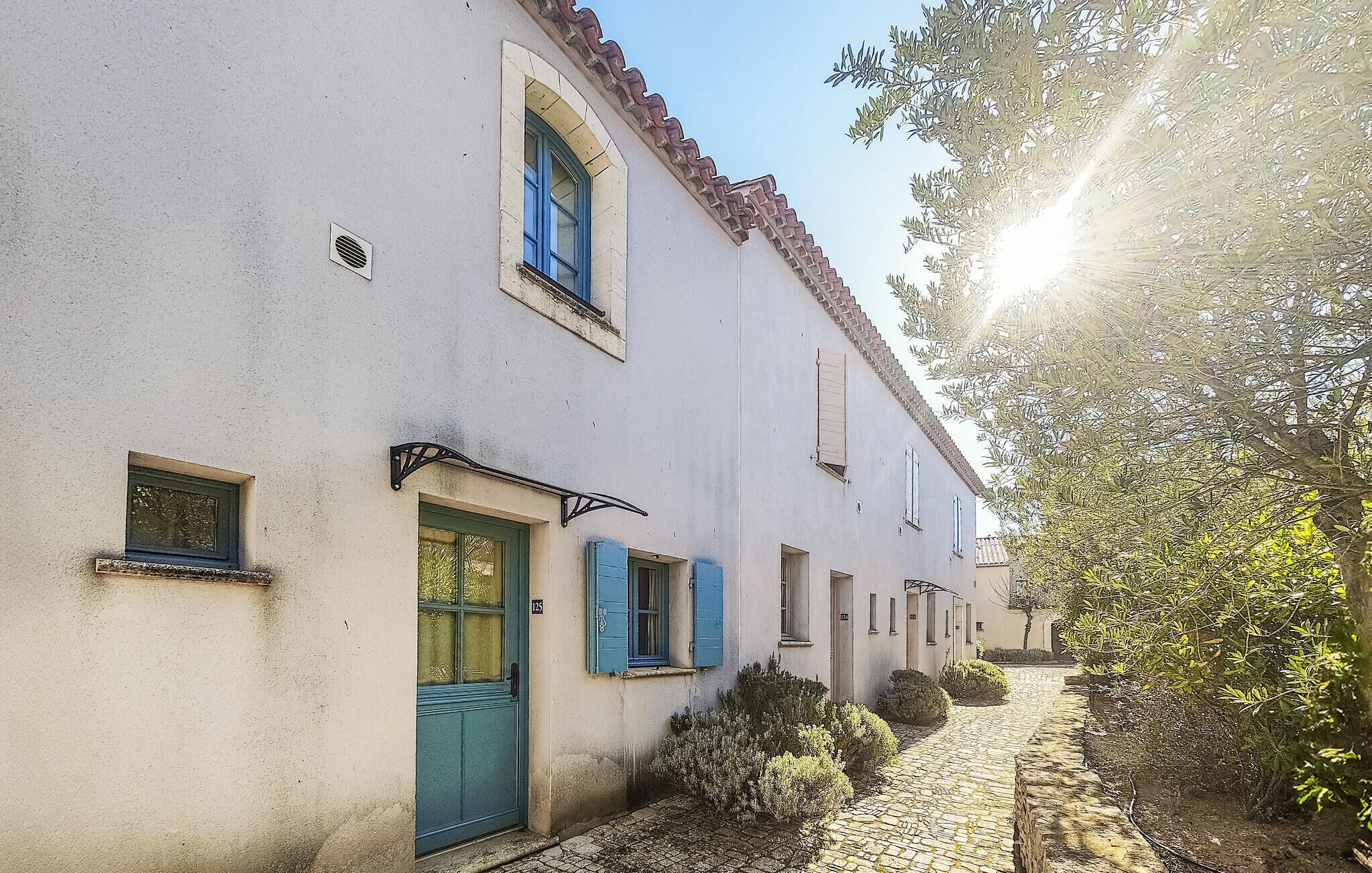 A narrow cobblestone street flanked by traditional buildings with white walls and blue shutters.