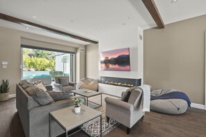 A modern living room with a sofa, armchairs, a coffee table, and a fireplace.