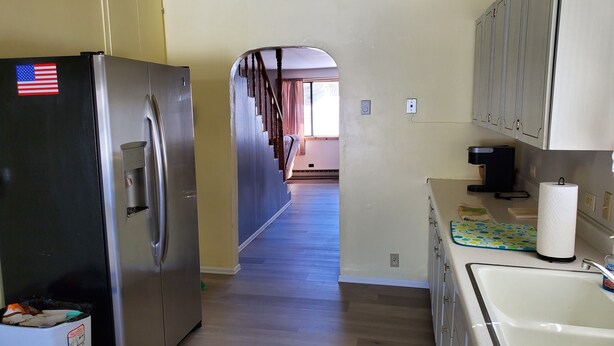 Una cocina con nevera de acero inoxidable, un lavabo y armarios.