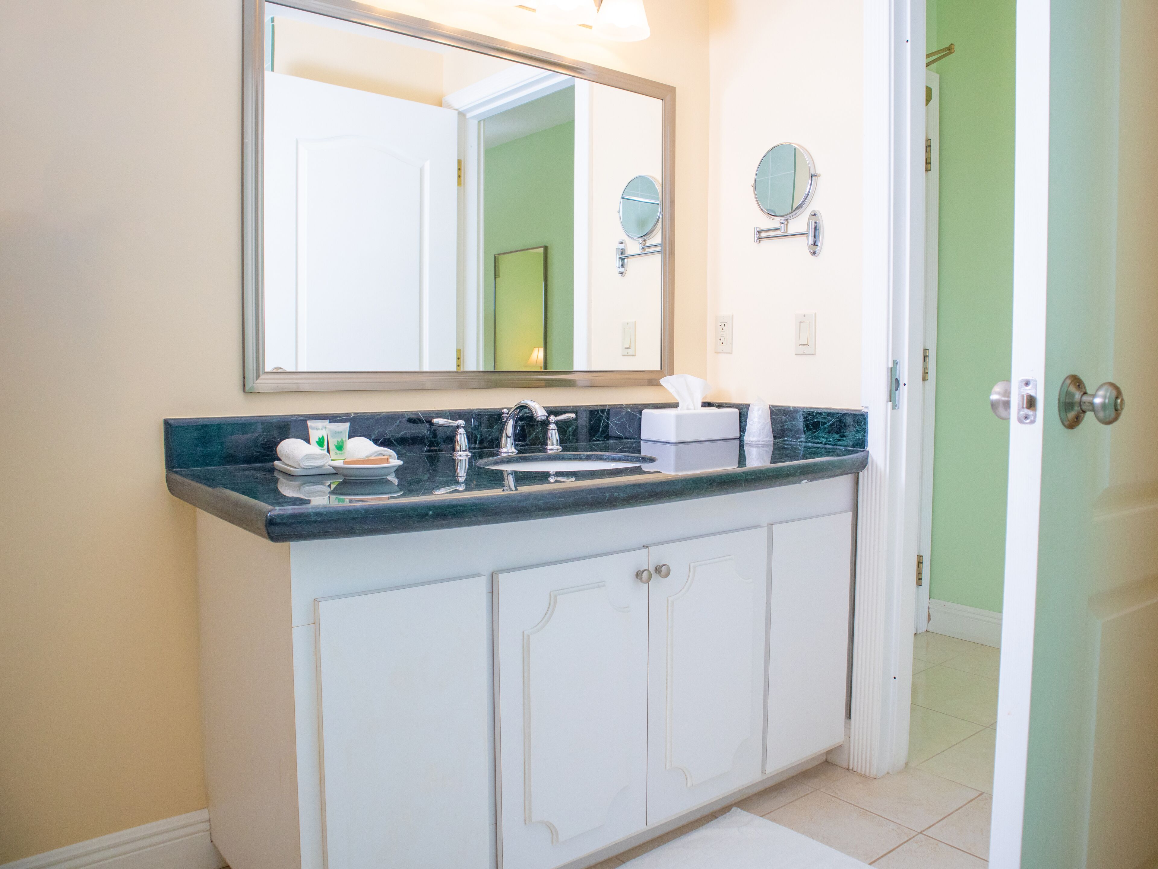 A bathroom with a large mirror, a sink, and a towel rack.