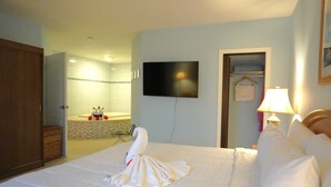 A hotel room with a bed, a television, a bathroom with a bathtub, and a towel shaped like a swan. - Princess Vegas Hotel & Casino (Corozal)