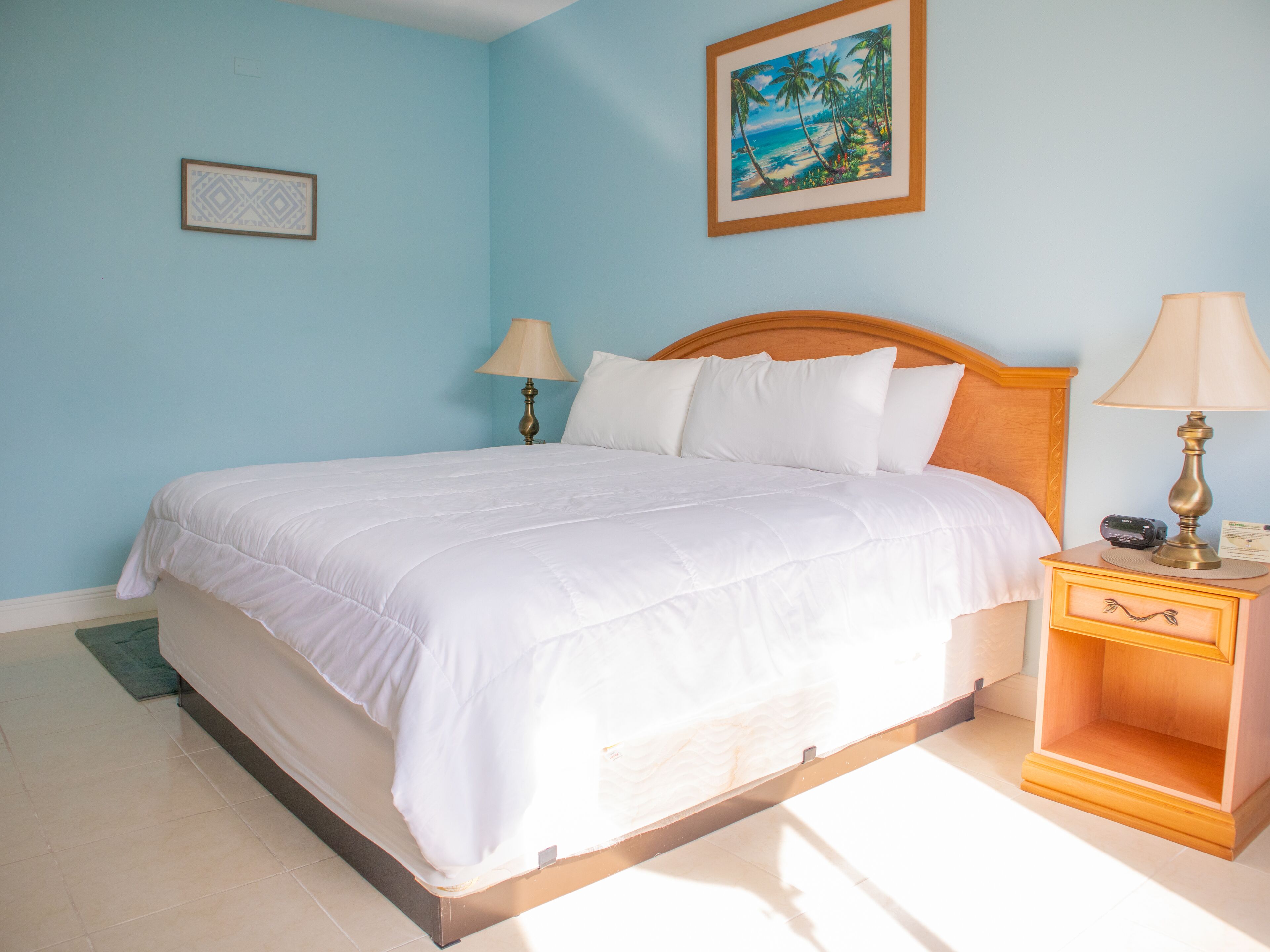 Una cama bien hecha con sábanas blancas en una habitación con paredes azul claro.